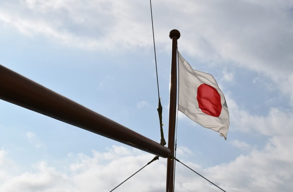 Mavi gökyüzü önünde dalgalanan Japon bayrağı